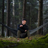 Uomo seduto nella foresta su un fuorilegio grigio nero di Caviera Alpin Loacker 